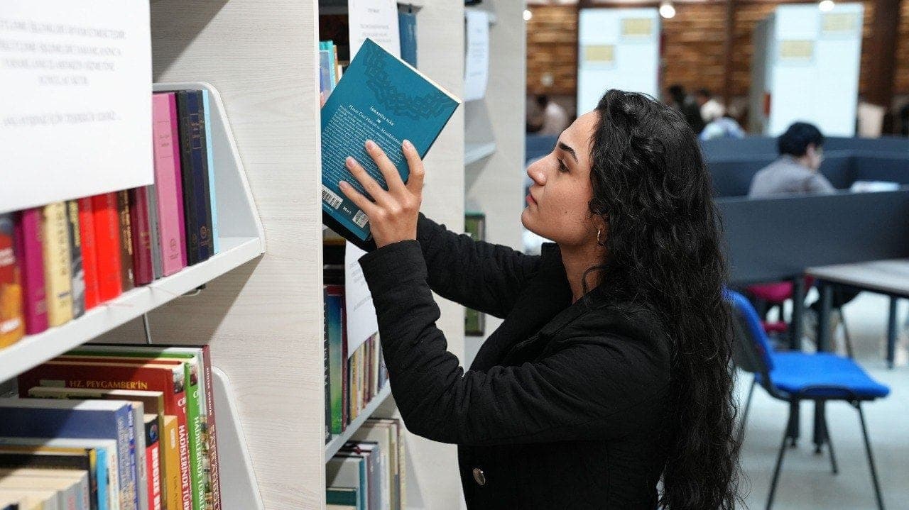 Raflardan kitap seçen öğrenci